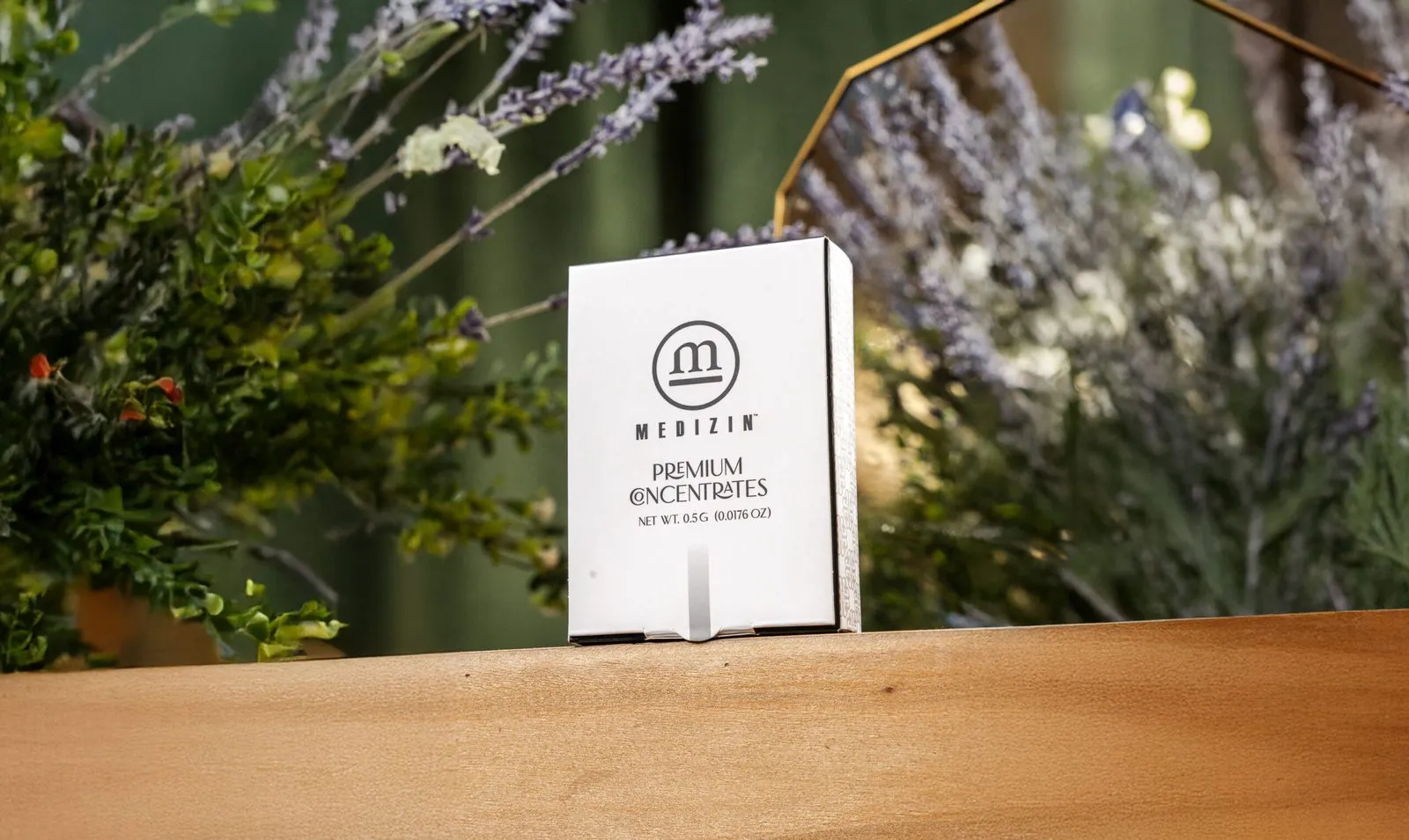 A Medizin Premium Concentrates box on a wooden shelf among dried herbs