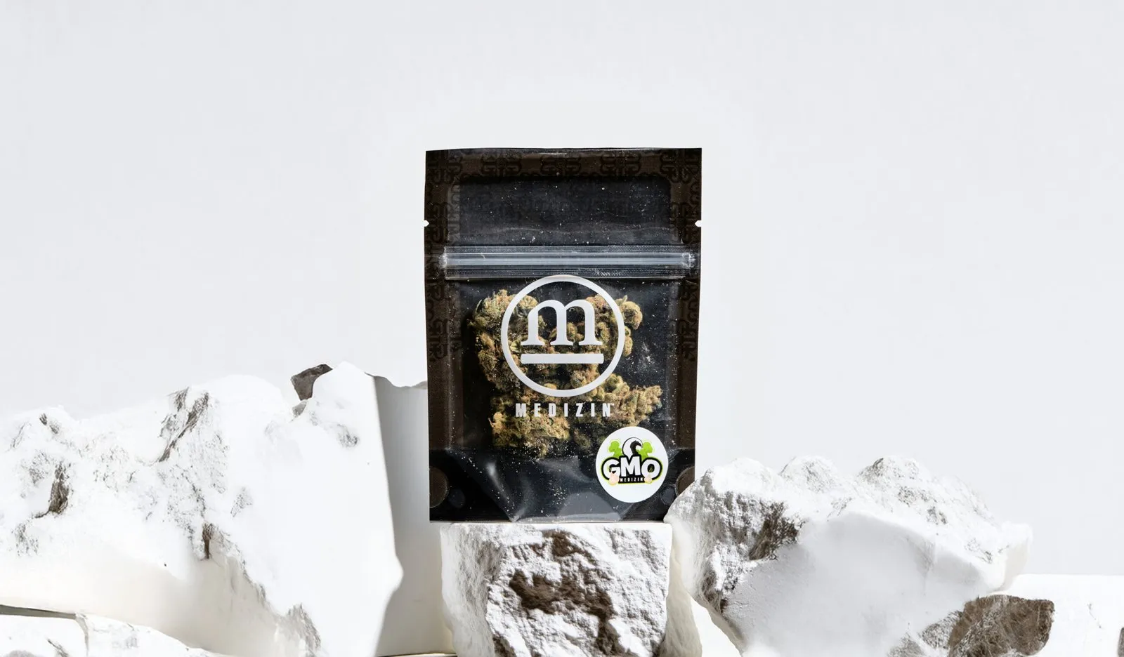 A Medizin flower pouch with its strain sticker, among white stones