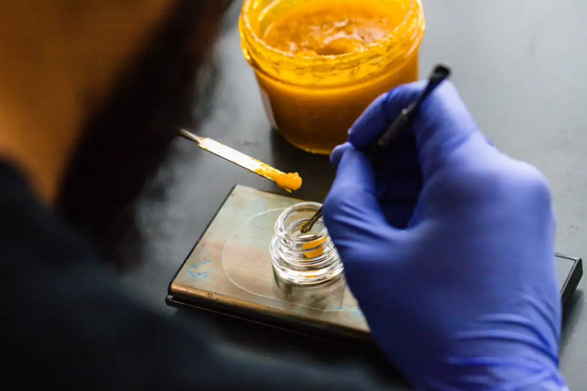 Man putting cannabis wax into the glass container