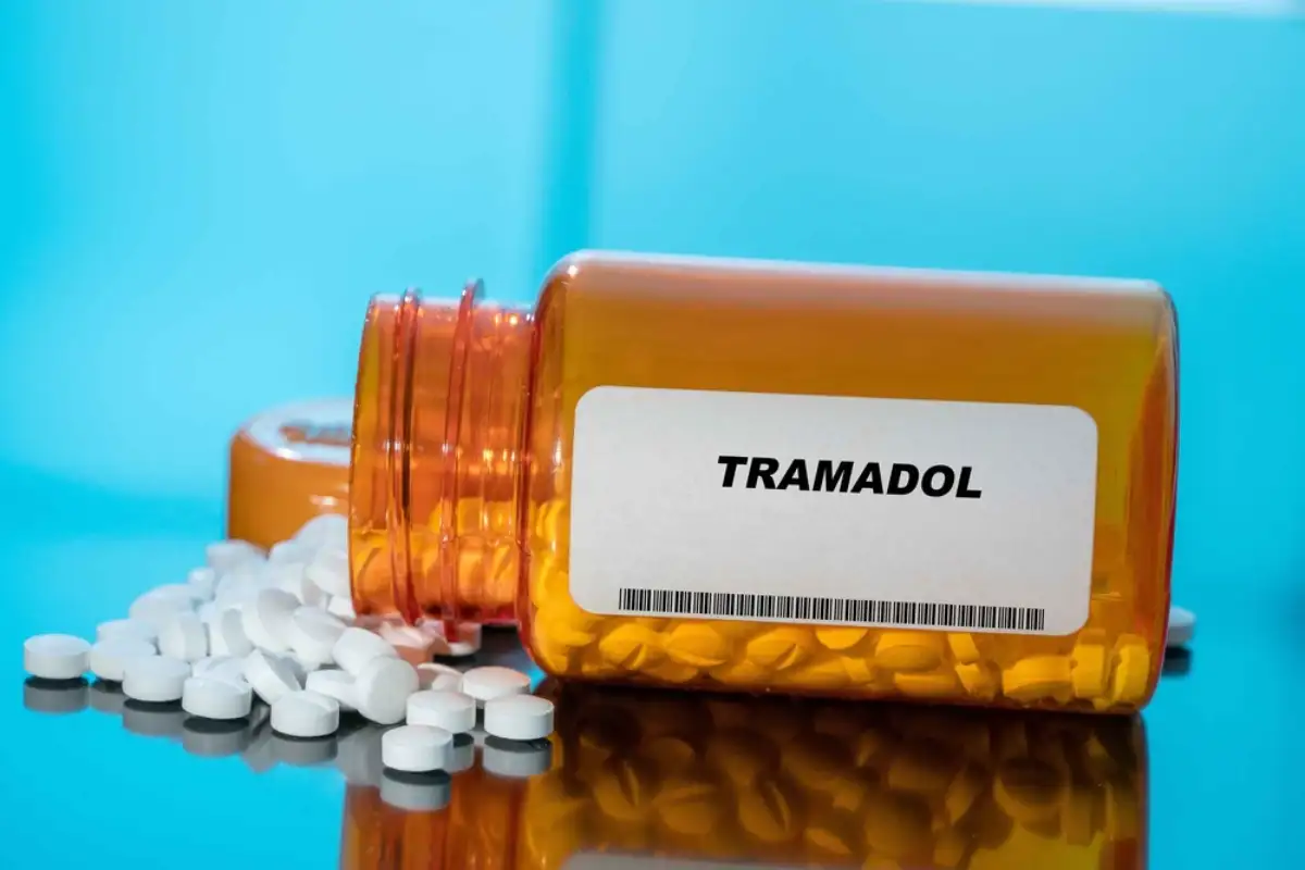Tramadol white medical pills and tablets spilling out of a drug bottle