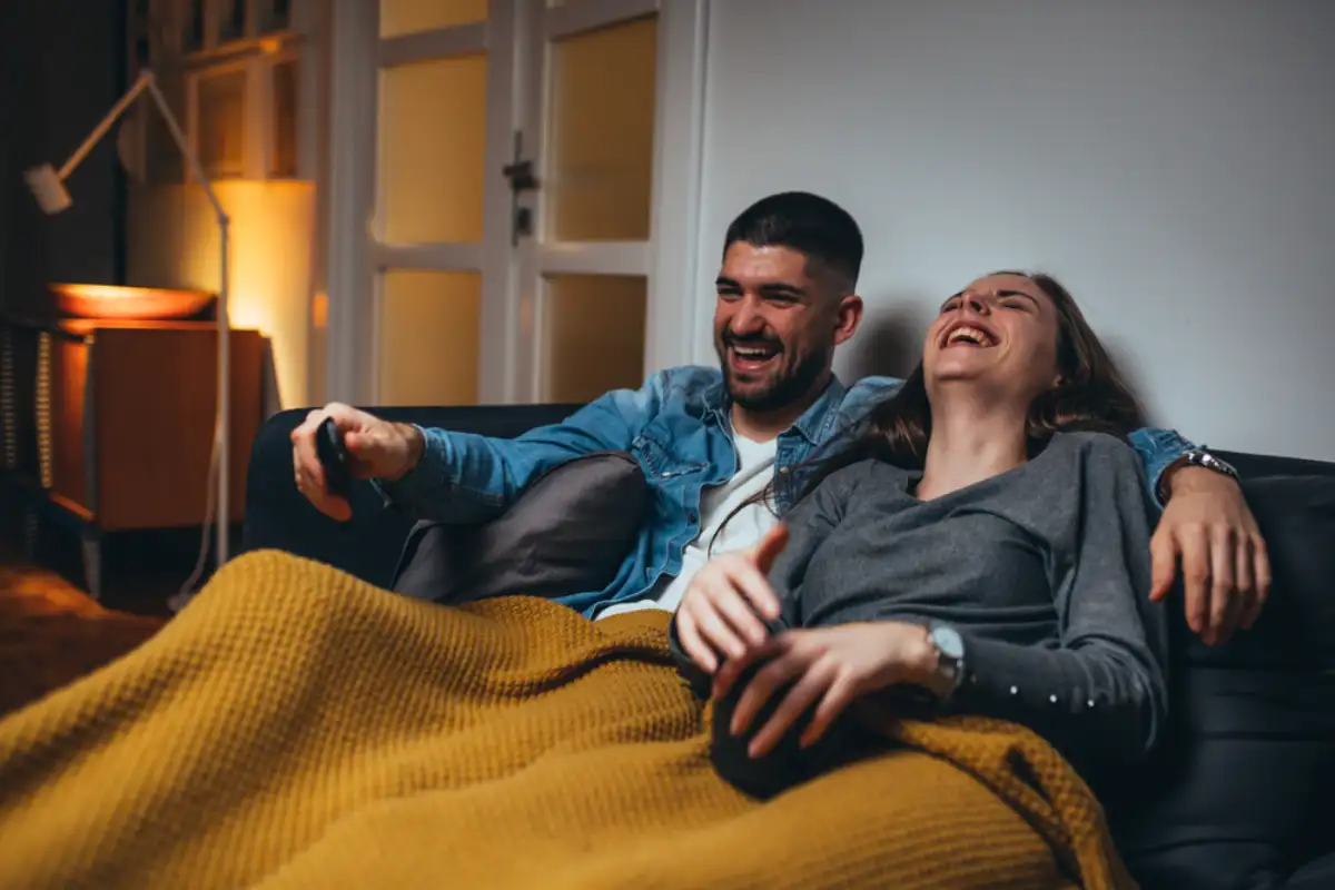 romantic couple laying sofa in their living room watching movie