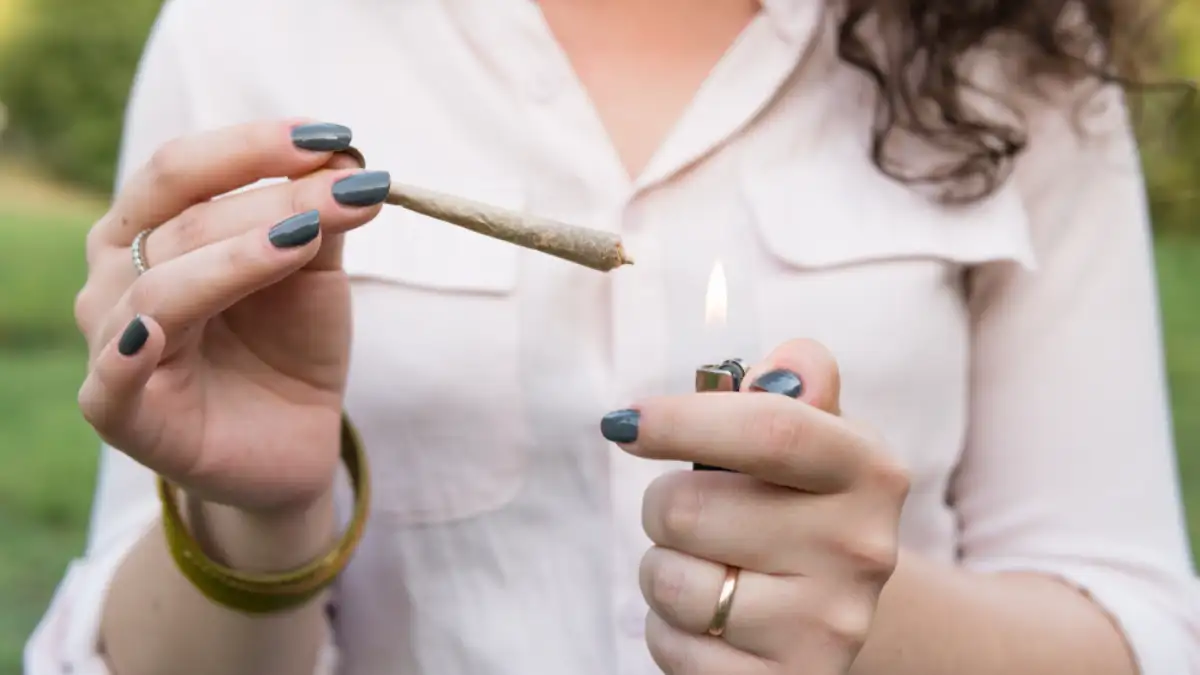 Young person smoking cannabis joint outdoors