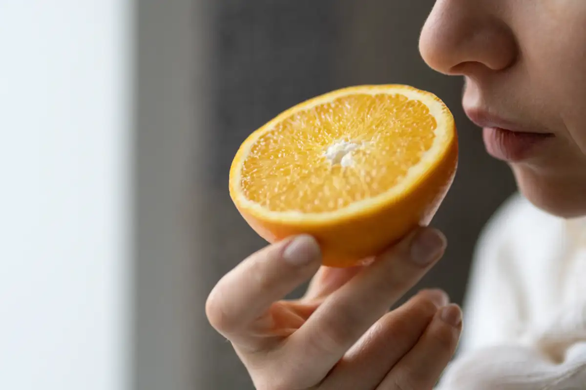 Woman trying to sense smell of half fresh orange