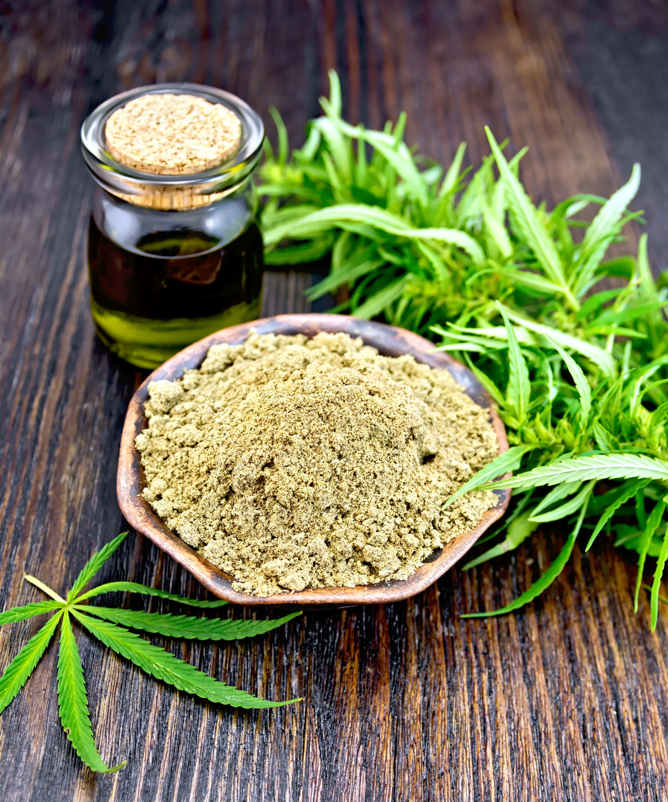 Flour hemp in bowl with oil and leaf on board