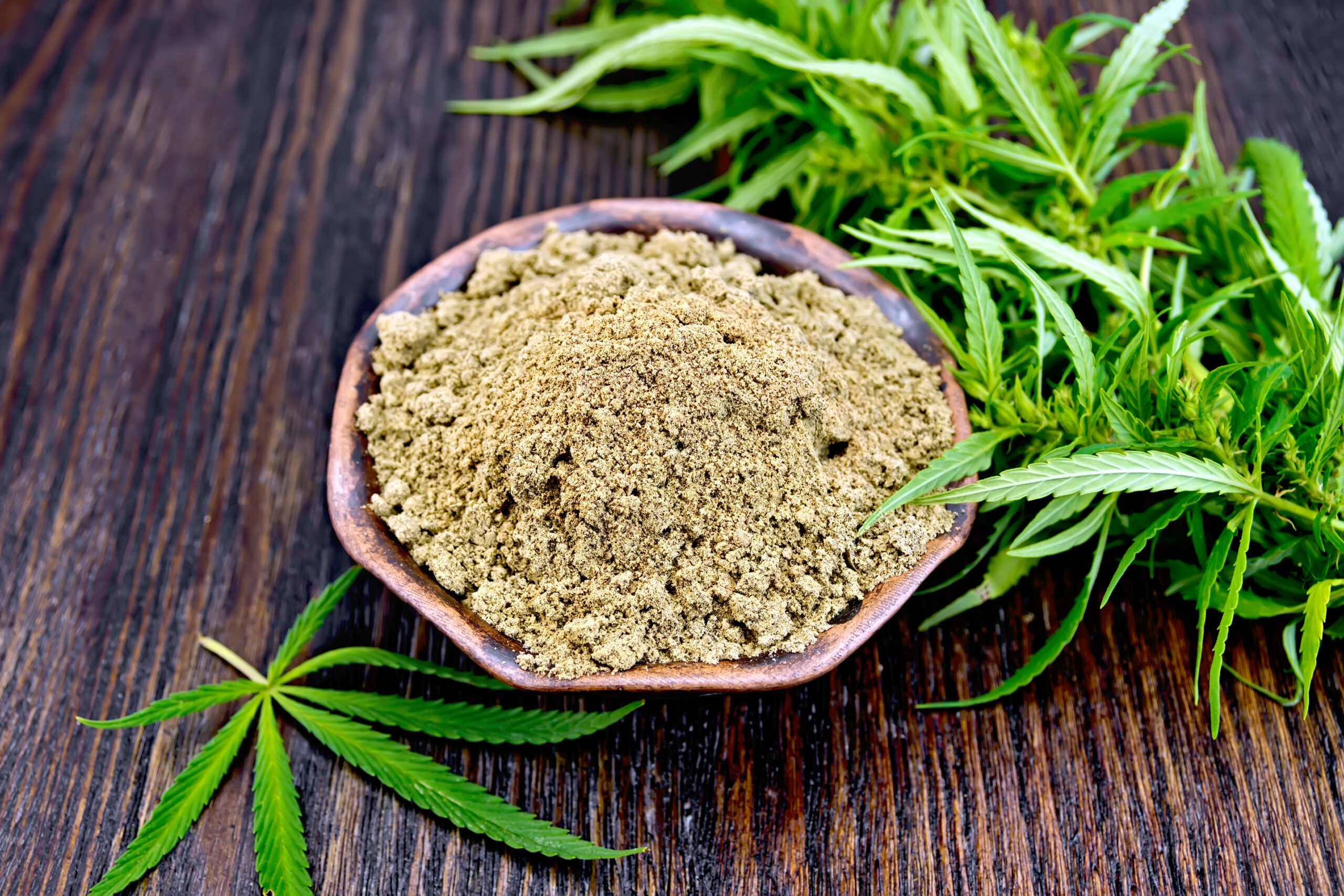 Flour hemp in clay bowl with leaf on board