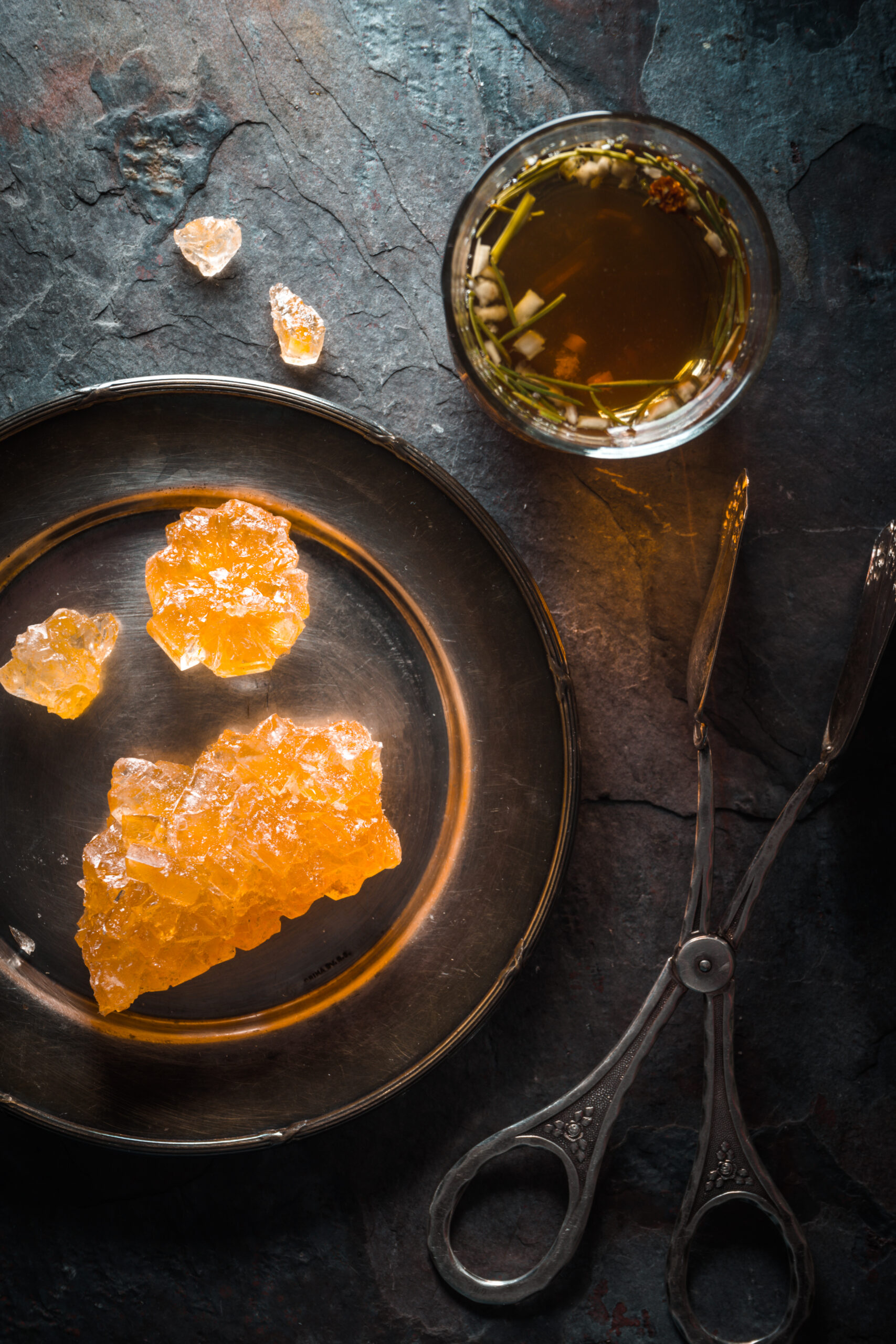 Grape sugar, tea and tongs on gray slate close up vertical
